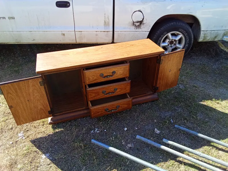 This solid wood minibar, bureau, or entertainment cabinet is a versatile storage piece with classic styling and plenty of usable space. It features two side cabinet doors, three center drawers, and a wide, flat top—perfect for use as a home bar, TV stand, buffet, or bedroom storage. The warm wood finish and traditional hardware give it a timeless look that fits well in living rooms, dining areas, bedrooms, or offices. The cabinet doors open to generous storage space, ideal for bottles, glassware, electronics, or household items. $50